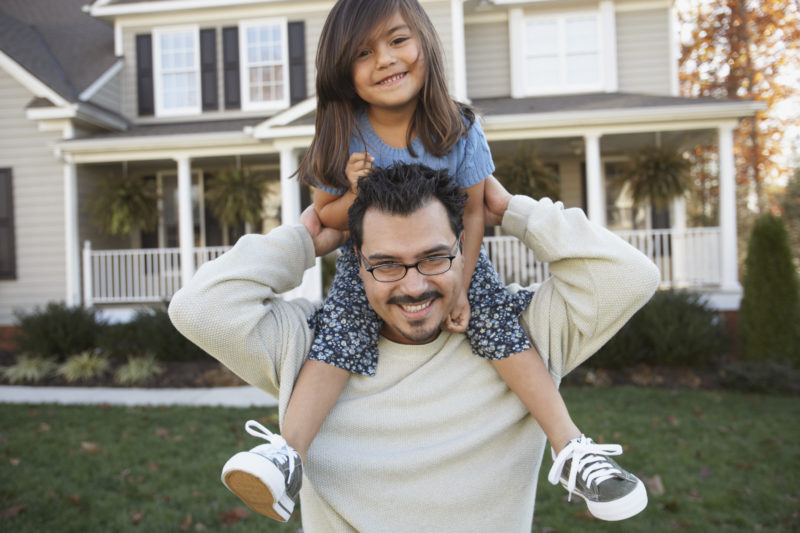 Portrait of father and daughter in front of house