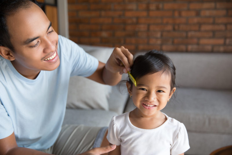 dad help her daughter to comb her hair at home