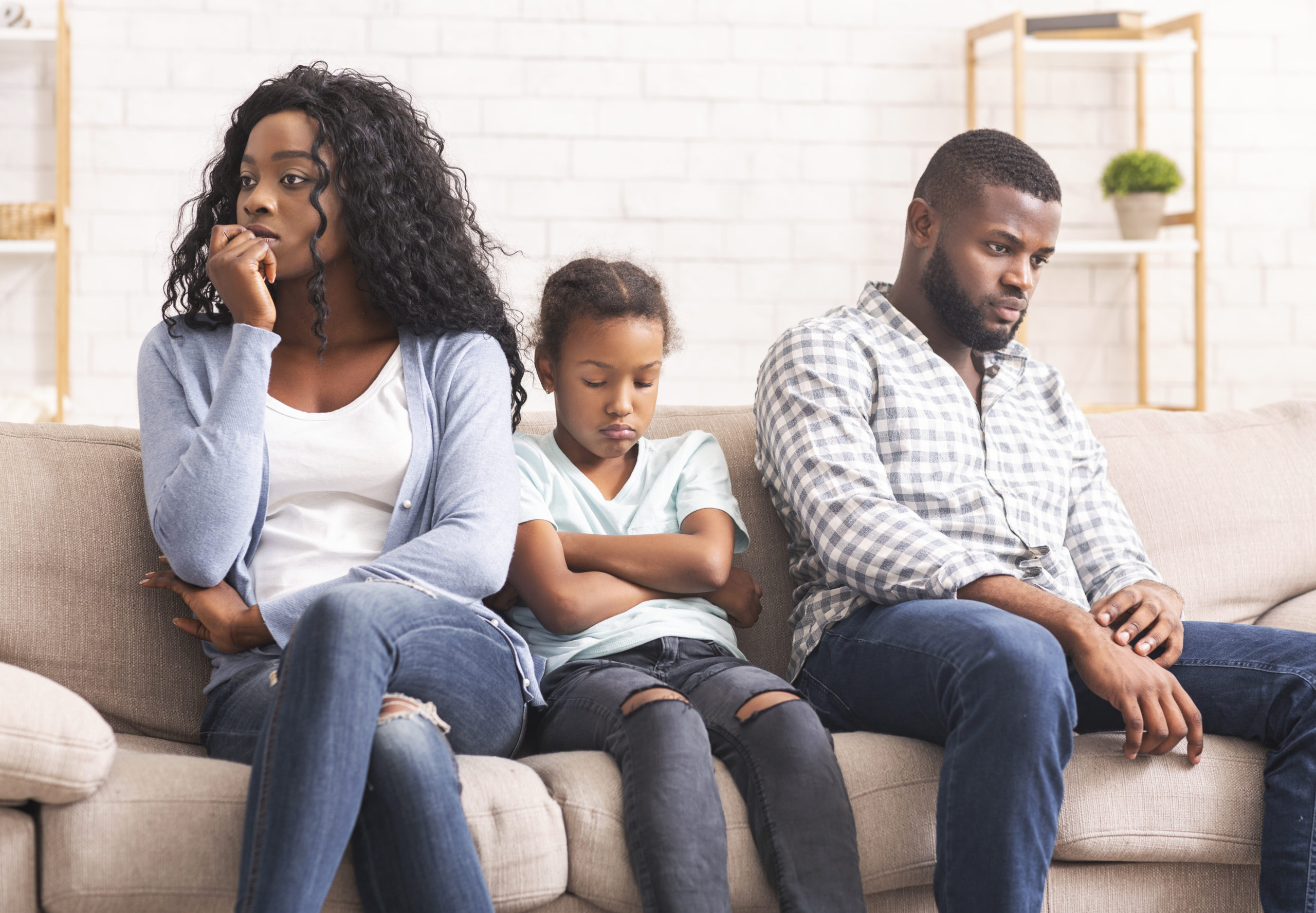 Upset black girl suffer from family conflict, sitting between offended parents, feeling depressed and frustrated.